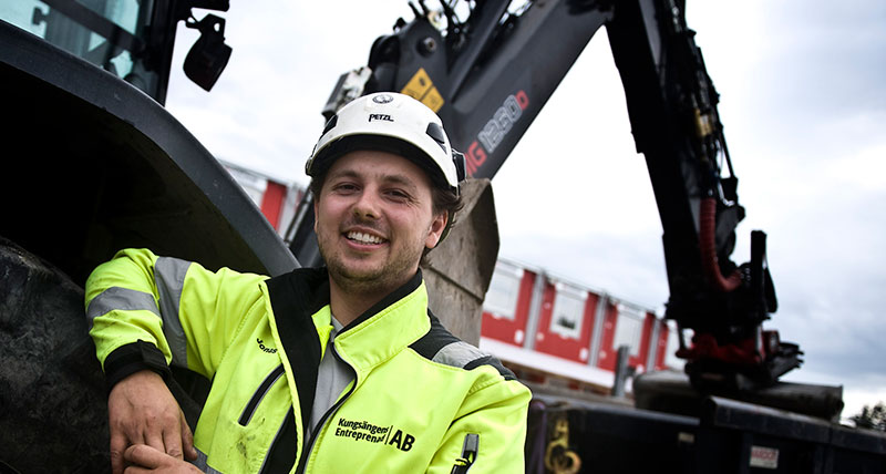Jonas Kilsgård framför en traktorgrävare från Huddig med maskinstyrning från Leica Geosystems